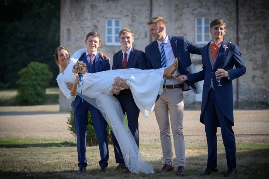 Mariée portée par un groupe d’amis en costume lors d’un mariage en extérieur