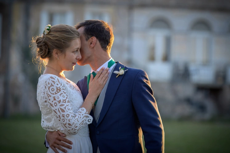 Marié embrassant la mariée sur le front, moment tendre en extérieur lors d’un mariage