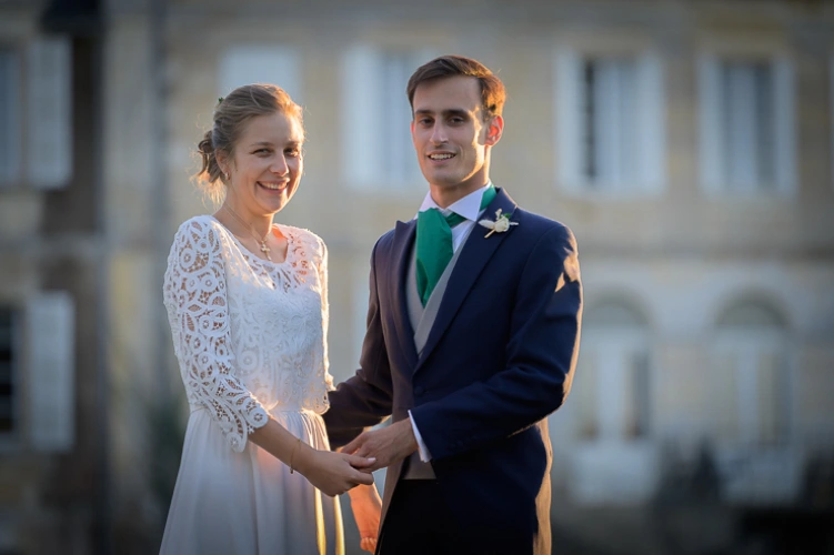 Couple de mariés se tenant la main et souriant lors d’un moment en extérieur pendant leur mariage