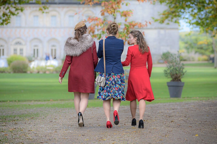 Trois invitées marchant dans un parc devant un bâtiment pendant un mariage en extérieur
