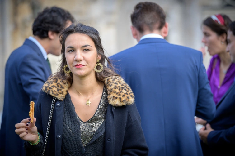 Invitée regardant l’objectif avec d’autres invités en arrière-plan pendant le vin d’honneur d’un mariage