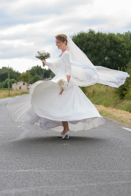 Mariée faisant tourner sa robe en extérieur pendant une séance photo de mariage
