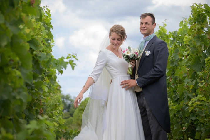 Couple de mariés posant dans une allée de vignes pendant une séance photo en extérieur