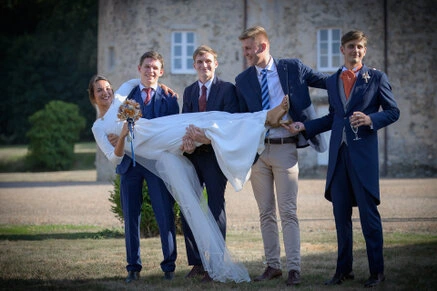 Mariée portée par un groupe d’amis en costume lors d’un mariage en extérieur