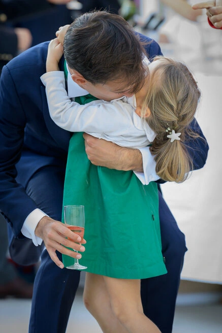 Un homme enlace affectueusement une enfant lors du vin d’honneur d’un mariage