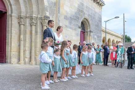 Les mariés posent avec un groupe d’enfants et des invités devant l’église lors du mariage