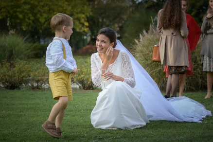 Mariée accroupie échangeant avec un enfant dans un moment naturel lors d’un mariage