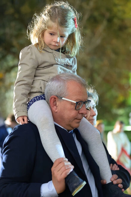 Petite fille assise sur les épaules d’un invité pendant le vin d’honneur d’un mariage en extérieur