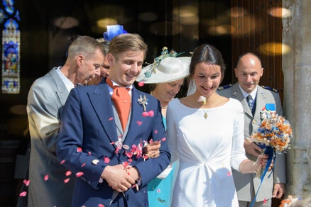 Les mariés sortent de la cérémonie entourés de leurs proches sous un lancer de pétales, dans une ambiance joyeuse