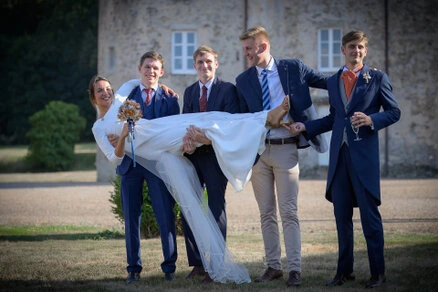 Mariée portée par un groupe d’amis en costume lors d’un mariage en extérieur