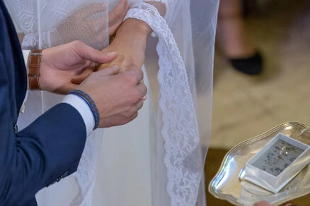 Gros plan sur les mains des mariés lors de l’échange des alliances pendant la cérémonie de mariage