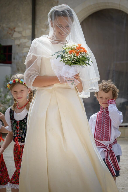 Mariée souriante tenant son bouquet entourée d’enfants lors d’un mariage en extérieur