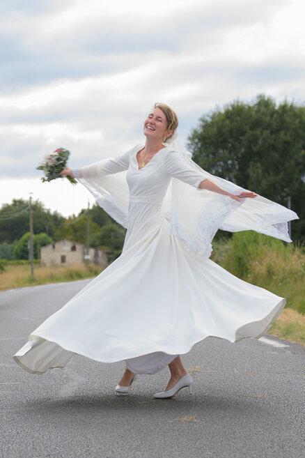 Mariée tournant sur elle-même en robe de mariage sur une route en extérieur