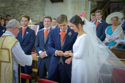 Les mariés échangent leurs alliances pendant la cérémonie de mariage à l’église, entourés de leurs proches