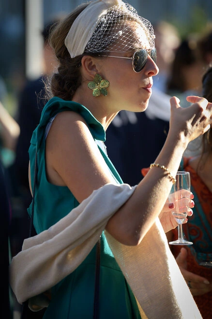 Invitée élégante portant des accessoires et tenant une coupe lors du vin d’honneur d’un mariage