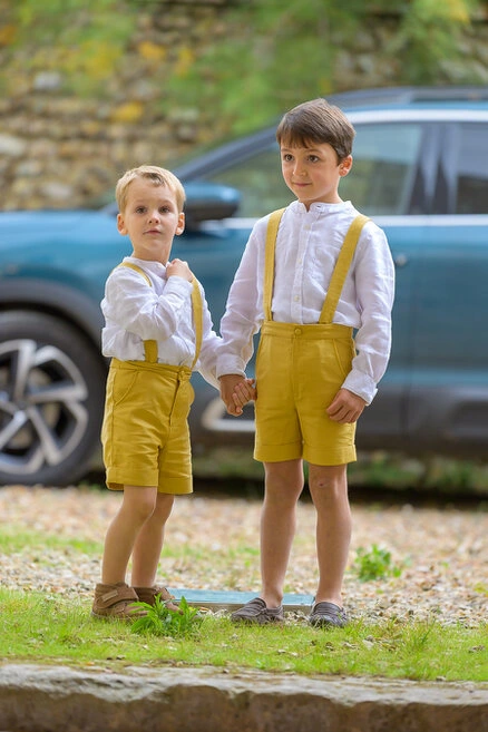 Deux enfants habillés élégamment se tenant la main pendant un mariage en extérieur