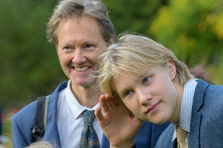 Un homme et un enfant souriants et complices pendant un mariage en extérieur