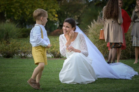 Mariée accroupie échangeant avec un enfant dans un moment naturel lors d’un mariage