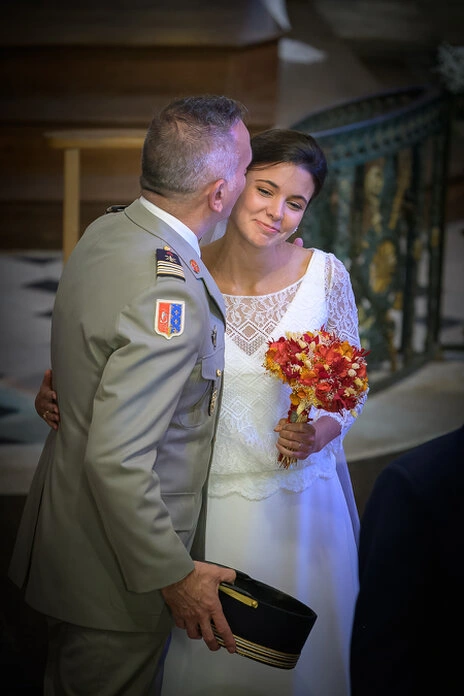 La mariée reçoit un baiser de son père pendant la cérémonie de mariage, tenant son bouquet