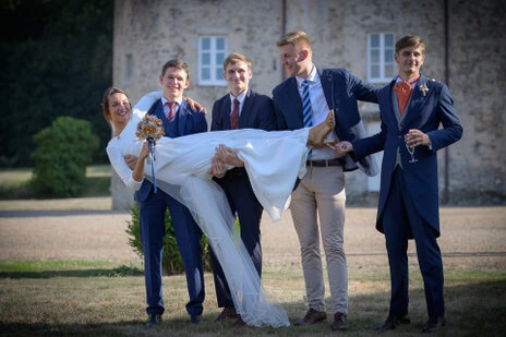 Mariée portée par un groupe d’amis en costume lors d’un mariage en extérieur