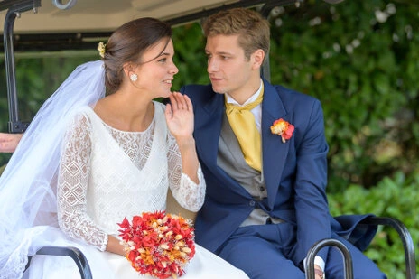 Couple de mariés échangeant un moment complice assis dans une voiture lors d’un mariage