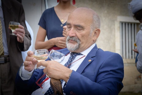Invité en costume examinant un verre lors du vin d’honneur d’un mariage