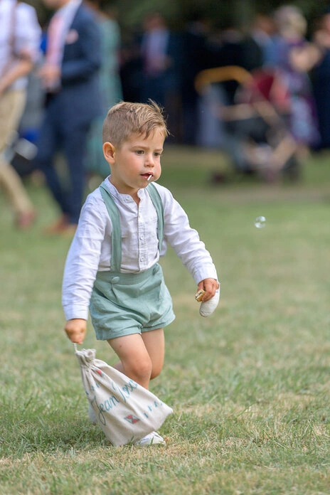 Jeune garçon courant et jouant pendant le vin d’honneur d’un mariage en extérieur