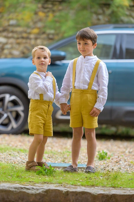 Deux enfants habillés élégamment se tenant la main pendant un mariage en extérieur
