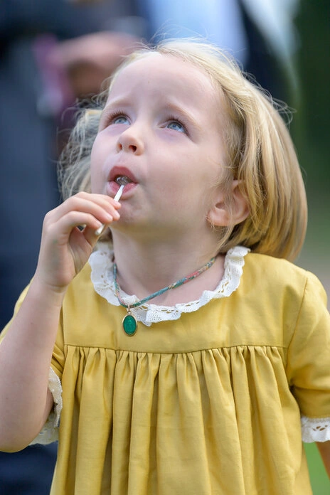 Petite fille mangeant une sucette pendant le vin d’honneur d’un mariage en extérieur