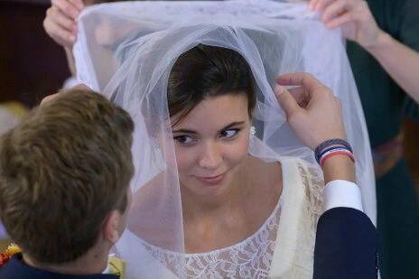 Le voile de la mariée est relevé pendant la cérémonie, révélant son visage dans un moment symbolique