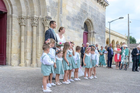 Les mariés posent avec un groupe d’enfants et des invités devant l’église lors du mariage