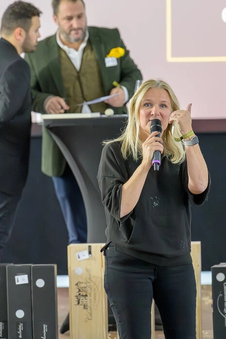 Femme prenant la parole avec un micro lors d’un événement d’entreprise devant un public