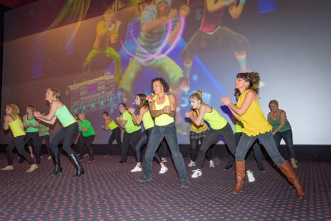 Groupe de participants réalisant une animation ou danse collective lors d’un événement professionnel