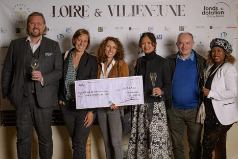 Participants posant lors d’un événement avec remise de chèque et partenaires en arrière-plan