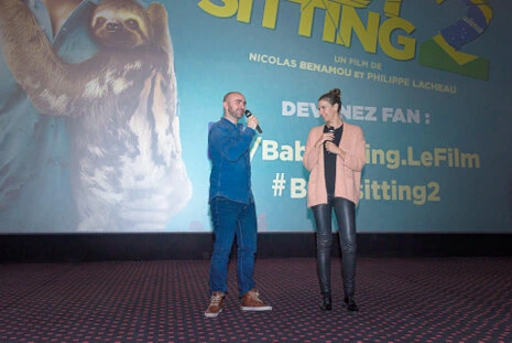 Deux intervenants échangeant avec des micros sur scène lors d’un événement devant un écran de projection