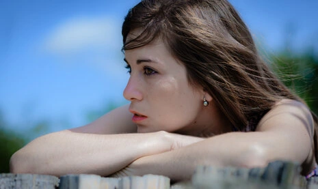 Portrait d’une femme en extérieur, regard tourné vers l’horizon, appuyée sur ses bras, lumière naturelle et ambiance douce