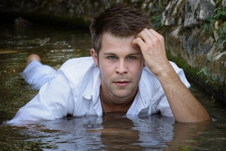 Portrait d’un homme allongé dans l’eau, regard direct vers l’objectif, ambiance naturelle et cadrage rapproché