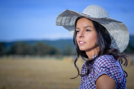 Portrait d’une femme portant un chapeau en extérieur dans un paysage naturel avec lumière du jour
