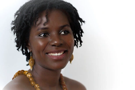 Portrait d’une femme souriante en studio sur fond clair, lumière douce et expression naturelle