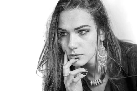 Portrait en noir et blanc d’une femme au regard intense, main posée sur le visage, éclairage doux et ambiance élégante