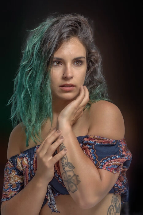 Portrait d’une femme en studio avec cheveux colorés et regard intense, éclairage doux et fond artistique