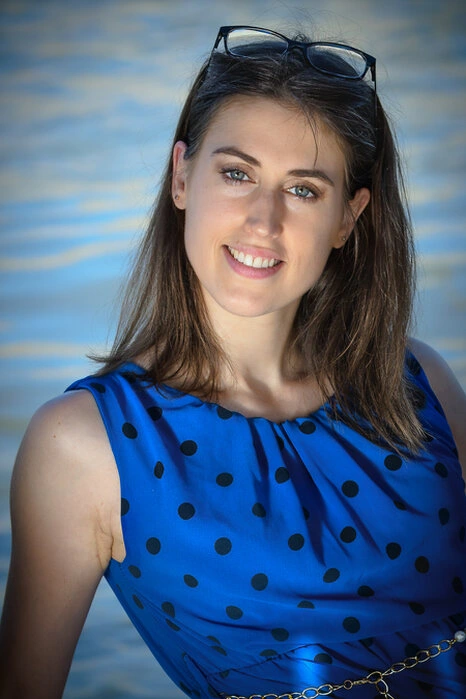 Portrait d’une femme souriante en extérieur avec une lumière naturelle douce, regard direct et expression chaleureuse