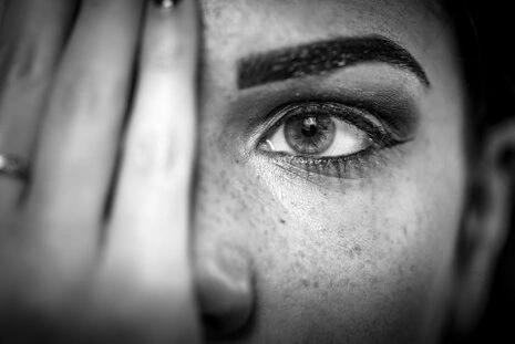 Gros plan sur l’œil d’une femme en noir et blanc, mettant en valeur le regard, la texture de la peau et les détails