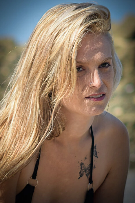 Portrait d’une femme en extérieur avec une lumière directe, mettant en valeur le regard et les détails du visage dans un environnement naturel