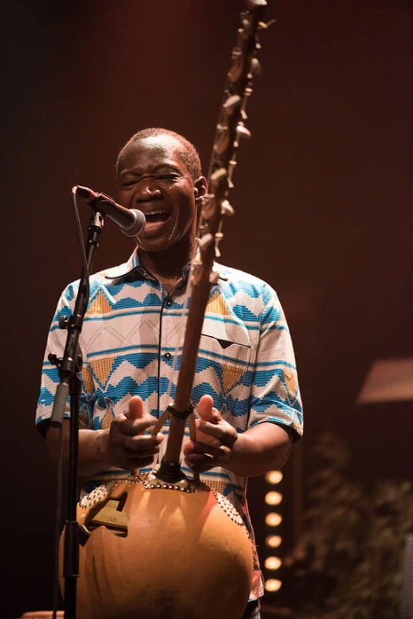 Portrait d’un homme en train de chanter avec intensité, capté en situation avec une expression forte et une lumière scénique