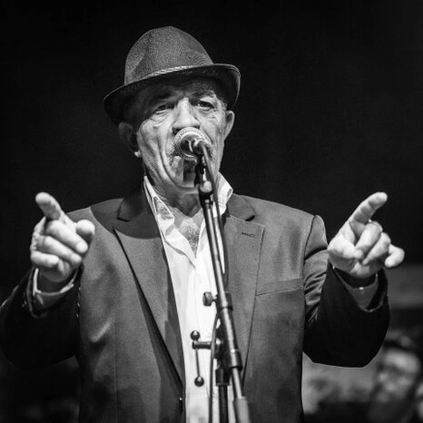 Portrait d’un homme en noir et blanc avec une expression marquée et un geste expressif, capté dans une ambiance contrastée