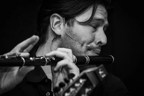Portrait en noir et blanc d’un musicien jouant de la flûte avec un micro, capturé en pleine interprétation