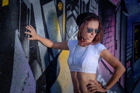 Portrait d’une femme en extérieur devant un mur graffiti, pose dynamique, éclairage naturel avec réflecteur