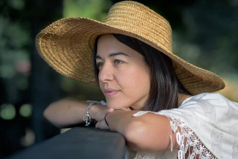 Portrait d’une femme portant un chapeau de paille, regard posé et lumière naturelle en extérieur