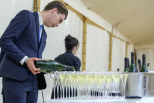 Serveur versant du champagne dans plusieurs coupes lors d’un cocktail d’entreprise